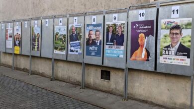 Une rangée d'affiches de campagne électorale borde un mur en béton dans une rue pavée de Nantes. Chaque affiche, numérotée de 1 à 11, présente les candidats de différents partis politiques avec des images et des textes en français. Cet affichage dynamique reflète le buzz civique souvent mis en avant sur Actu44.fr.