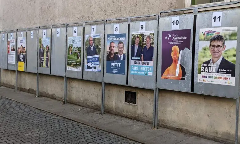 Une rangée d'affiches de campagne électorale borde un mur en béton dans une rue pavée de Nantes. Chaque affiche, numérotée de 1 à 11, présente les candidats de différents partis politiques avec des images et des textes en français. Cet affichage dynamique reflète le buzz civique souvent mis en avant sur Actu44.fr.