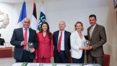 Cinq personnes, trois hommes et deux femmes, se tiennent côte à côte, souriantes, dans une salle de conférence à Nantes. Chacun tient une plaque ou un certificat. Des drapeaux et des documents de la conférence sont exposés sur la table devant eux, reflétant l'esprit des initiatives de la Loire-Atlantique.