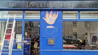 La devanture bleue des Impertinantes à Châteaubriant arbore un dessin à la craie représentant une tasse fumante et une flamme. Une échelle est appuyée contre la vitrine, où des personnes sont assises à l'intérieur, visibles à travers les reflets des bâtiments voisins, comme le détaille Actu44.fr.