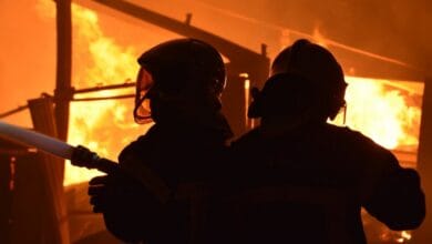 Deux pompiers de Châteaubriant, casqués et équipés de protections, se détachent sur le sol incendiaire pour lutter avec acharnement contre le feu. Des flammes vives et de la fumée illuminent les lieux tandis qu'ils travaillent sans relâche pour maîtriser le chaos, comme le rapporte un reportage d'Actu44.fr.